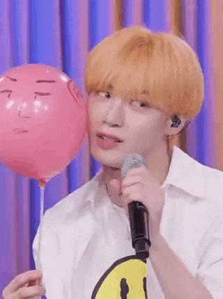 a man is holding a pink balloon and a microphone .