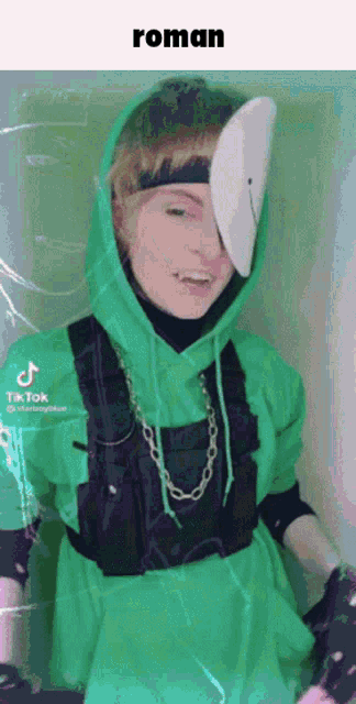 a person wearing a green hoodie and a white mask with the word roman on the bottom right