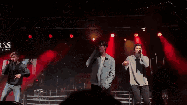 a group of young men are standing on a stage with red lights behind them .