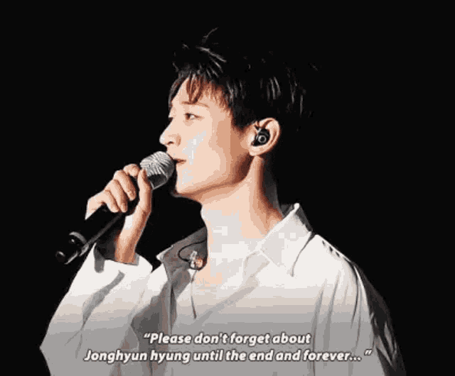 a young man is singing into a microphone while wearing earbuds .
