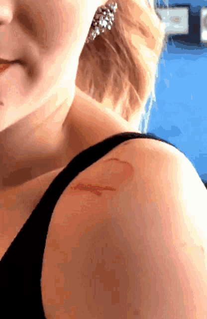 a close up of a woman 's shoulder with a tattoo of a heart on it