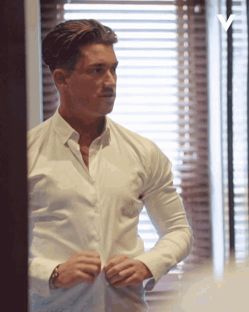 a man in a white shirt is adjusting his sleeves