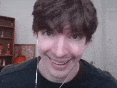 a young man wearing headphones is smiling and making a funny face .