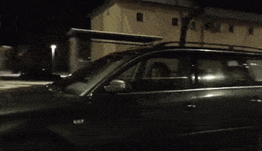 a black car is parked in front of a house