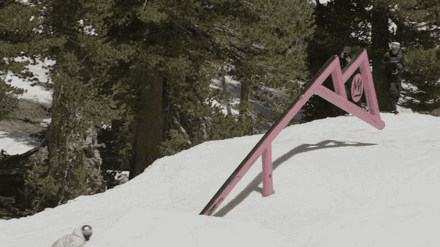 a snowboarder is doing a trick on a pink rail with a smiley face on it