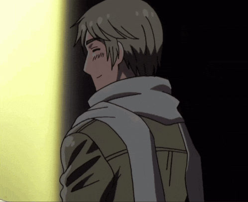 a man with a scarf around his neck is smiling in a dark room
