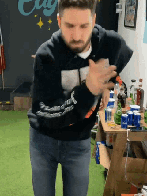 a man standing in front of a table full of cans and bottles including one that says bud light