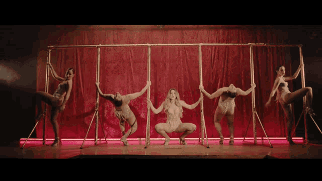 a group of women are dancing on a stage with a red curtain in the background