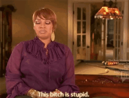 a woman in a purple shirt is sitting in front of a pool table and saying `` this bitch is stupid '' .