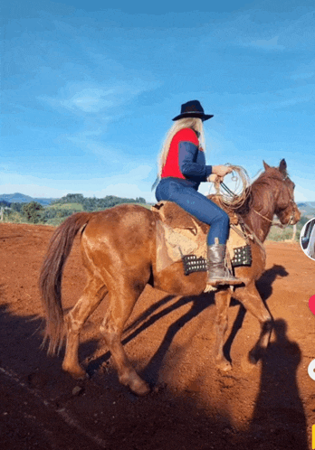 a woman is riding a brown horse on a dirt field