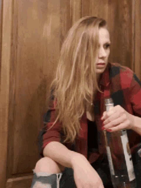 a woman in a plaid shirt holds a bottle of water