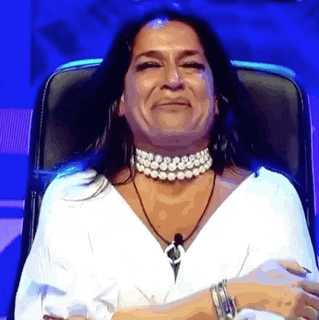 a woman is sitting in a chair with her hands folded and smiling .