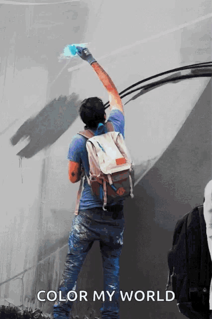 a man with a backpack paints a wall with the words color my world below