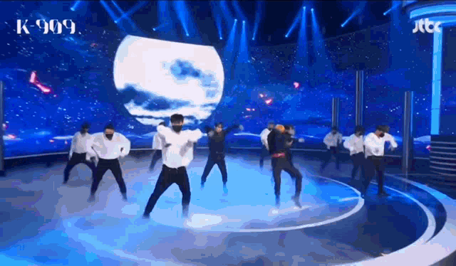 a group of men are dancing on a stage with jtbc written on the bottom