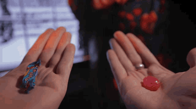 a person is holding a blue candy and a red candy in their hand