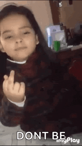 a little girl is giving the middle finger while sitting down .