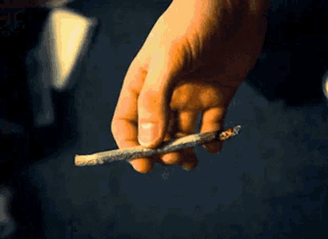 a close up of a person holding a cigarette in their hand