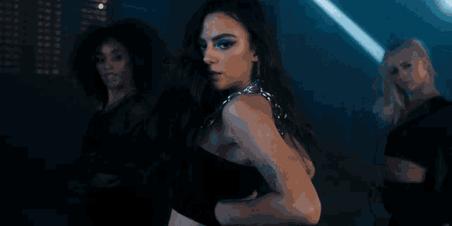a woman with a tattoo on her arm is dancing in front of two other women