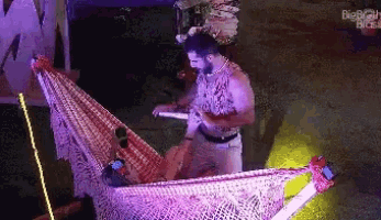 a man is standing next to a woman in a hammock with the big brother logo visible in the background