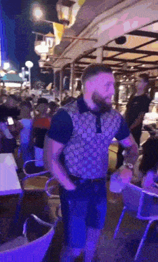 a man in a gucci shirt is dancing in a crowded bar .