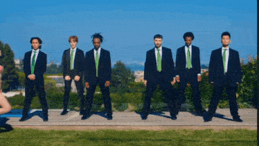 a group of men in suits and green ties standing in a line