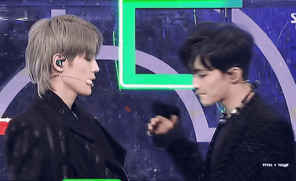 two men are standing next to each other in front of a green l