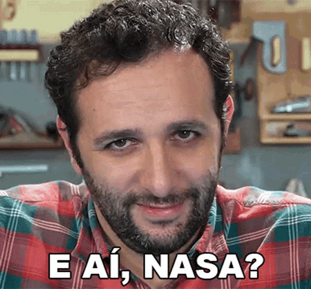 a man with a beard is wearing a plaid shirt and has the words e ai nasa written on his face .