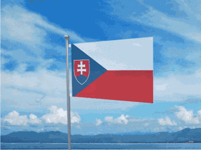 a flag with a cross on it is flying in front of a body of water