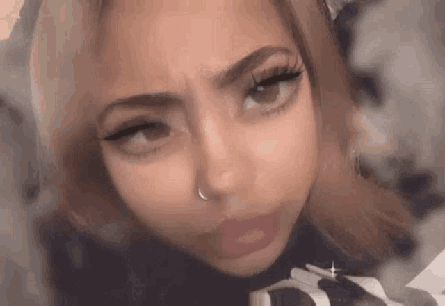 a close up of a woman 's face with a nose ring making a face .