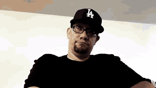 a man wearing a la hat looks at the camera