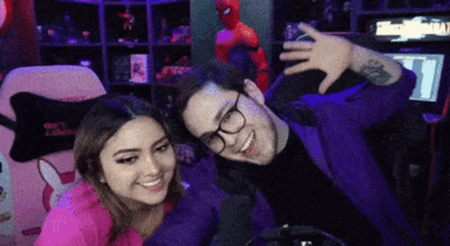 a man and a woman are posing for a picture in front of a computer monitor .