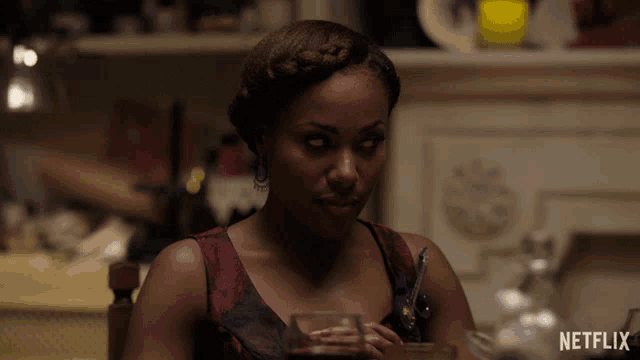 a woman is sitting at a table with a netflix logo behind her