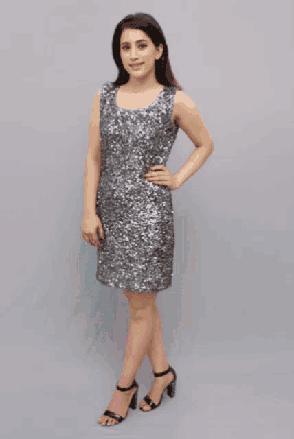 a woman in a pink sequined dress is standing in front of a grey wall