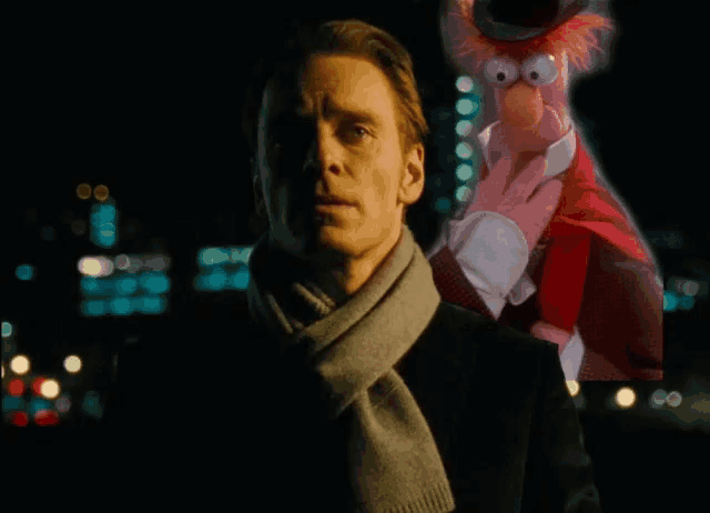 a man wearing a red scarf stands next to a stuffed animal