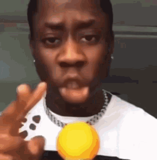 a man is holding a yellow ball in his hand and making a funny face .