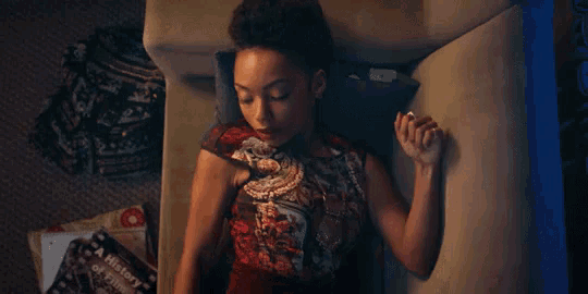 a woman is laying on a couch reading a history of love book