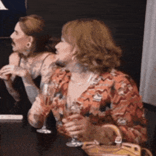 two women are sitting at a table drinking wine