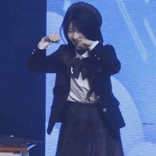 a girl in a school uniform is standing in front of a blue screen