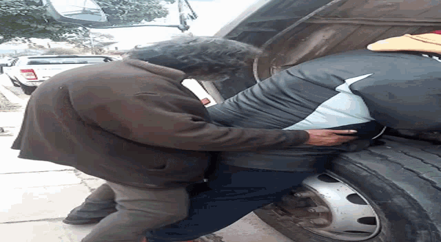 a man in a brown jacket is holding another man in a black shirt