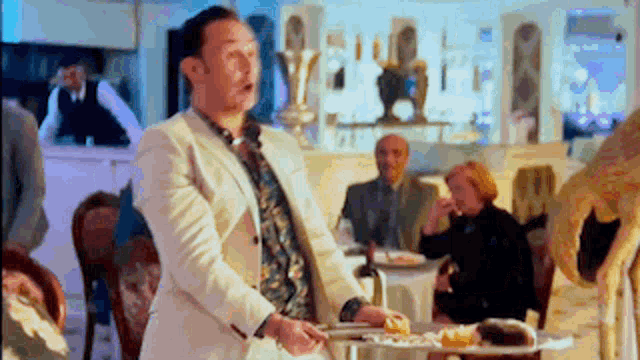 a man in a white suit is holding a tray with food on it