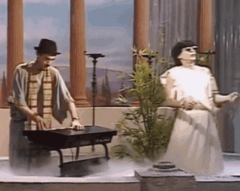 a man in a hat is playing a keyboard next to a woman in a white dress who is singing into a microphone .