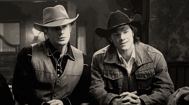two men wearing cowboy hats and jackets sit next to each other