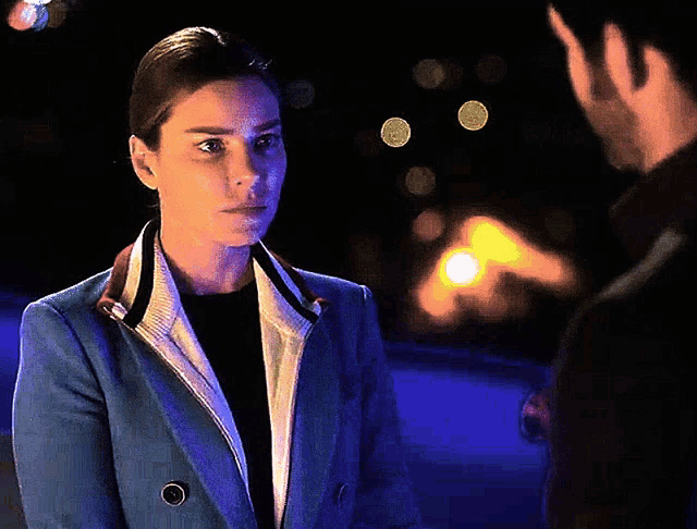 a woman in a blue jacket stands next to a man in a black suit