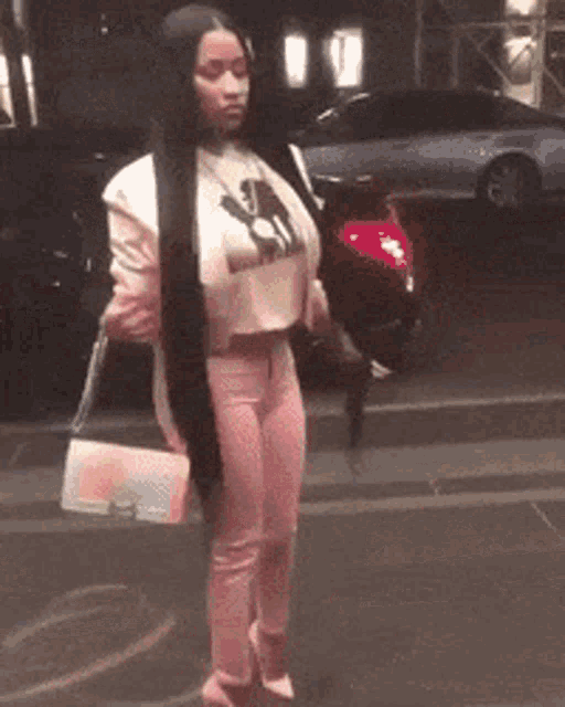 a woman with long black hair is walking down the street holding a pink purse