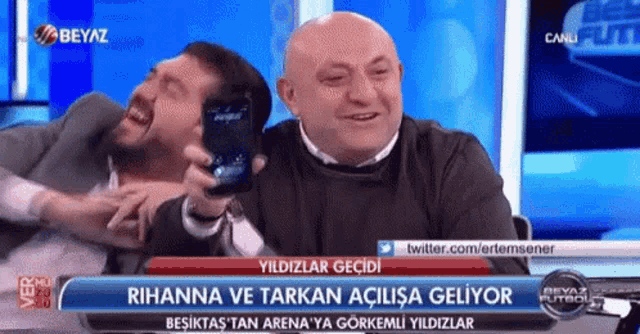 two men are laughing in front of a blue screen that says beyaz