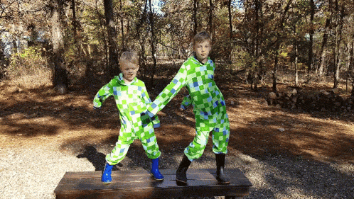 two young boys in green and blue pajamas are holding hands