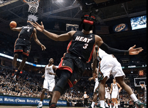 a basketball player wearing a heat jersey is being fouled