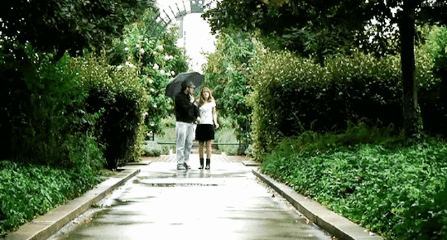 a man and a woman walking down a path in the rain with an umbrella