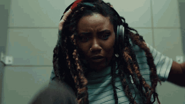 a woman with dreadlocks is wearing headphones and a striped shirt