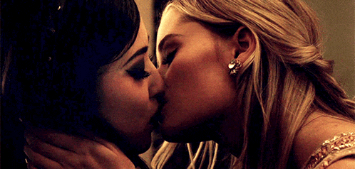 two women are kissing each other in front of a mirror .